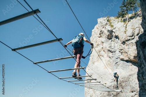 Climber on via ferrata  crossing suspended wire bridge photo