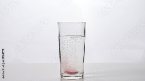 Effervescent tablet falls into a glass of water on a white background zoom in
