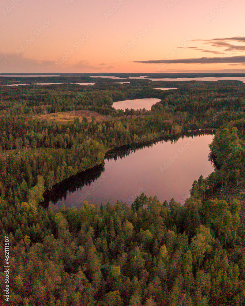 Aerial drone shot about lake middle of forest in sunset light