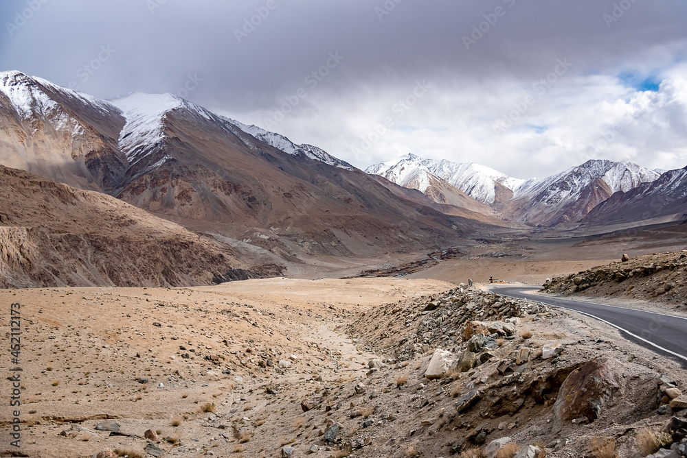 Beautiful panoramic view of a mountainside lit at the sunset period and also including of a snow found high up in the mountain peaks.	