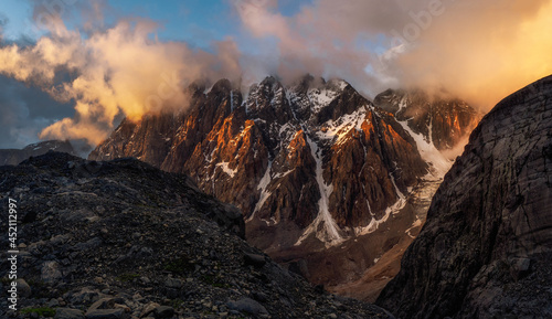 Majestic glacier is illuminated by the bright golden evening sun. Panoramic view. Altai Mountains.
