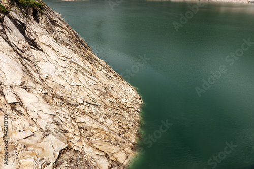 Rock cliff protrudes into the clear water. Natural background