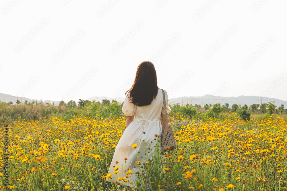 Fototapeta premium A woman standing on a yellow flower field