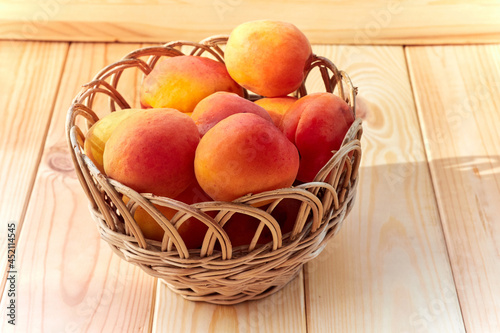 Apricots in a wicker basket on a wooden table