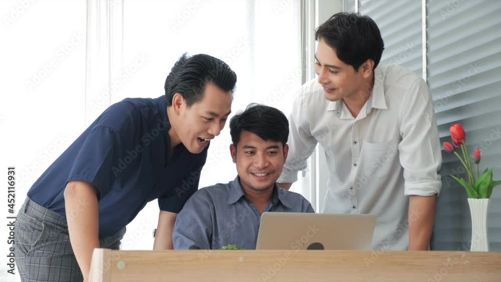 Happy Asian business team working in office. Smiling office workers using laptop computer. Meeting of businesspeople discuss at the computer. Happy Asian business team working in office. Smiling office workers using laptop computer. Meeting of businesspeople discuss at the computer.