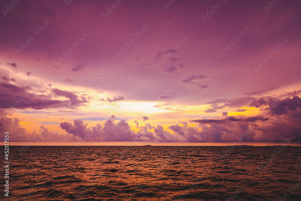 Beach sand, sea and blue sky with clouds. Nature in twilight period which including of sunrise over the sea and the nice beach. Summer beach with blue water and purple sky at the sunset.	