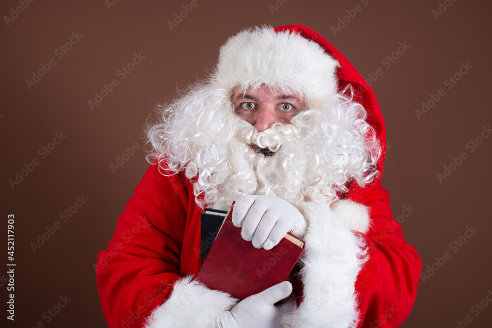 Funny Santa Claus reads books. Brown background.