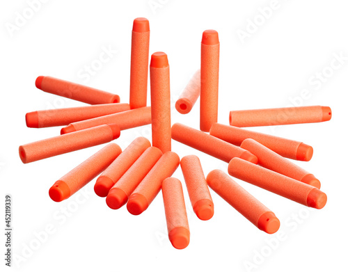 Scattering of orange plastic toy cartridges for pneumatic weapons with a soft tip, isolated on a white background.