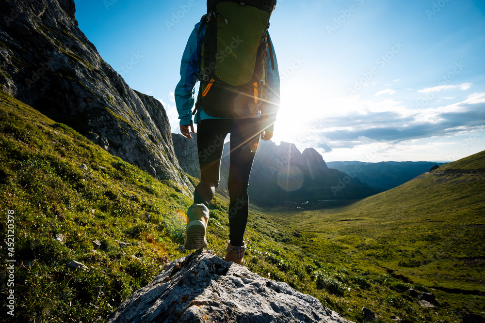 Successful woman backpacker hiking on sunset alpine mountain top - obrazy, fototapety, plakaty 