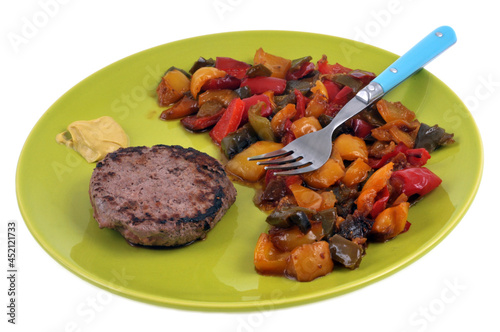 Assiette de poivrons cuits avec un steak haché et de la moutarde servis dans une assiette avec une fourchette en gros plan sur fond blanc photo