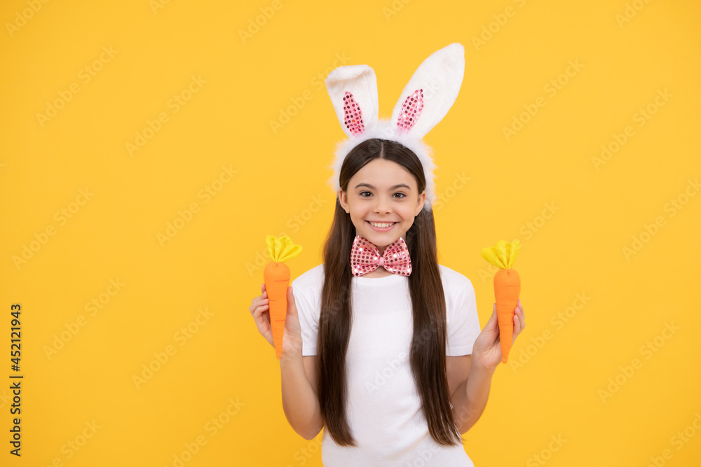 childhood happiness. child in rabbit ears and bow tie. time for fun. kid looking funny with carrot childhood happiness. child in rabbit ears and bow tie. time for fun. kid looking funny with carrot
