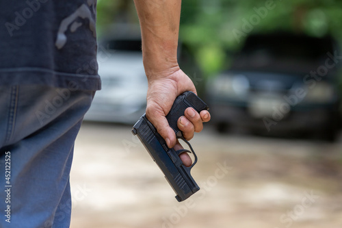 selective focus pistol man holding a gun by his side The concept of using a gun in public Leave space for text