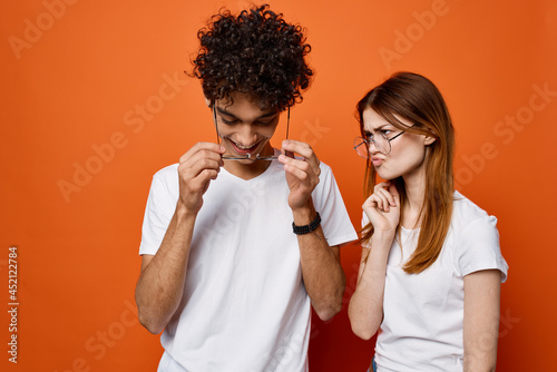 cheerful young couple in white t-shirts chatting orange background