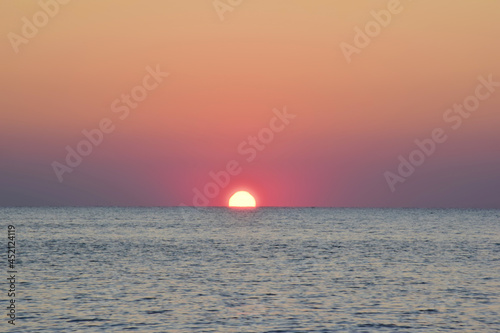 Fototapeta Naklejka Na Ścianę i Meble -  The morning sun half rose from the calm sea.
