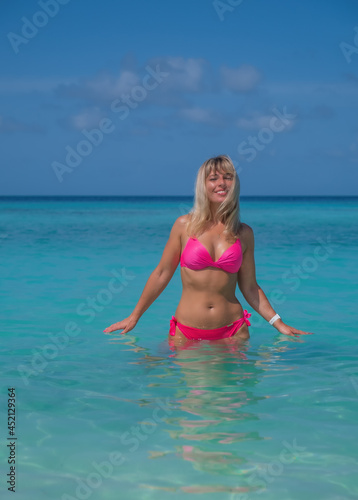 Beautiful blond woman in pink bikini by blue lagoon. Crossroads Maldives, indian ocean. Saii lagoon hotel, july 2021