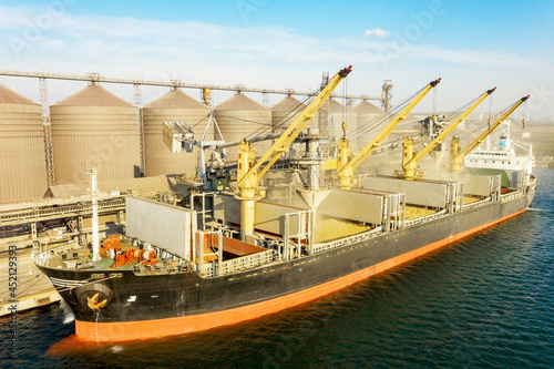 Loading grain into holds of sea cargo vessel through an automatic line in seaport from silos of grain storage. Bunkering of dry cargo ship with grain