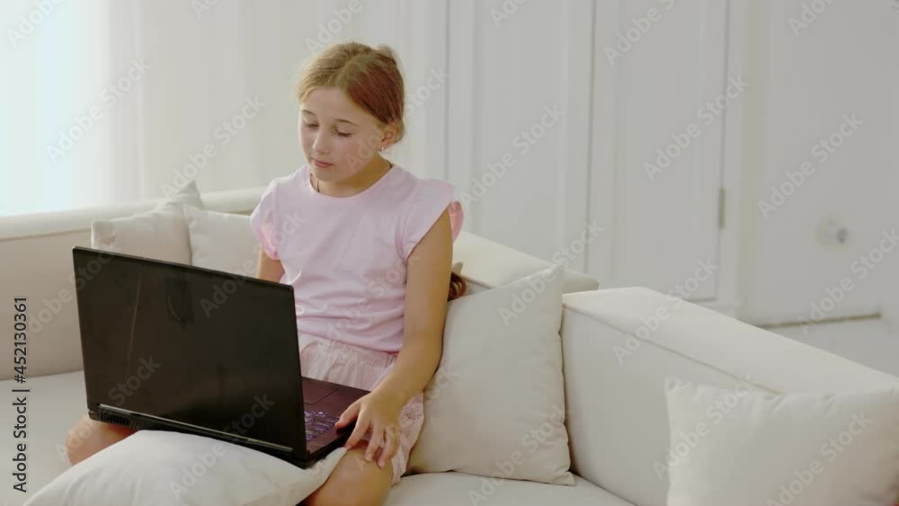 girl looking at laptop sitting on the couch girl looking at laptop sitting on the couch
