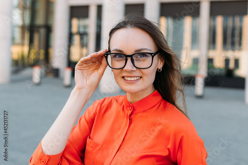 Woman thirties years old in stylish clothes straightens glasses photo