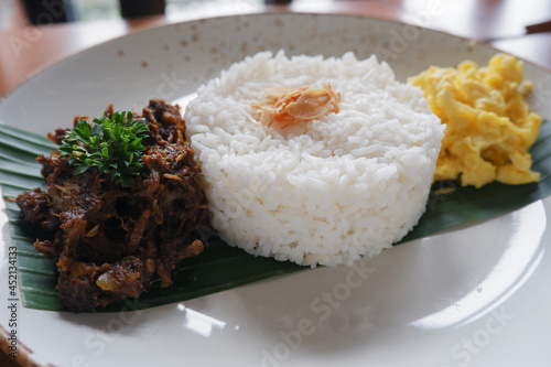 menu for food Madurese black herbs duck. This menu is a typical black jamu duck food from Madura, East Java with the addition of white rice and a few sprinkles of vegetables  photo