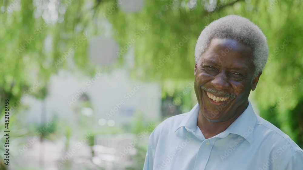 Portrait of relaxed senior man standing in garden at home after retirement turning towards and smiling at camera -shot in slow motion Portrait of relaxed senior man standing in garden at home after retirement turning towards and smiling at camera -shot in slow motion
