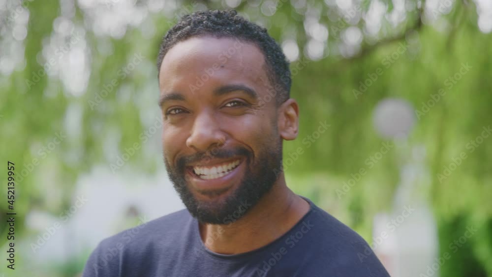 Head and shoulders portrait of relaxed man standing in garden at home after retirement smiling at camera -shot in slow motion Head and shoulders portrait of relaxed man standing in garden at home after retirement smiling at camera -shot in slow motion