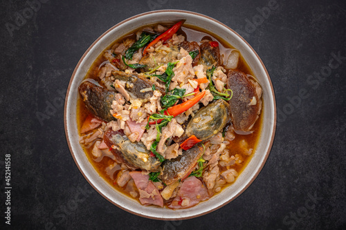 Pad Ka Prao Kai Yeow Ma, Thai food, basil stir fried century egg with pork and ham on dark tone texture background, top view