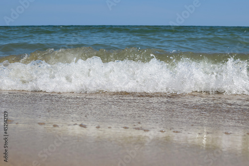 Sea waves roll on the sandy daytime beach
