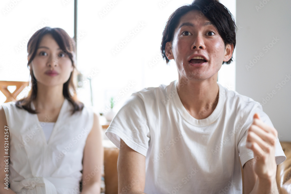 おうちでスポーツ観戦をするカップル おうちでスポーツ観戦をするカップル
