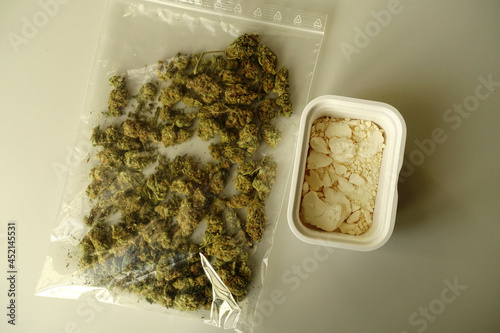 Dried Marijuana flower buds in a plastic bag and a jar with Amphetamine powder photo