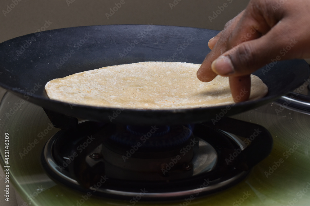 Making roti (Indian Chapati) on roti tawa made of wheat with hand
