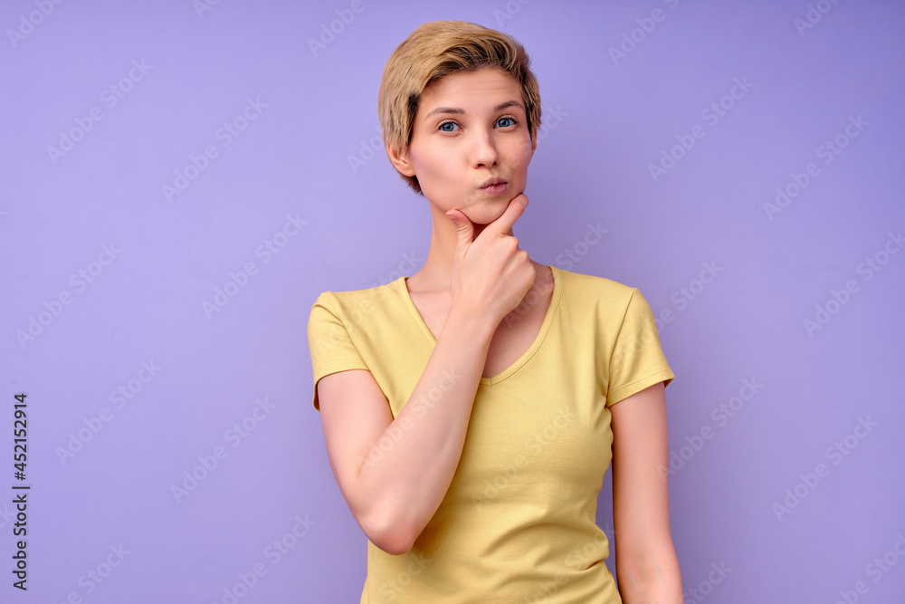 thoughtful female in casual outfit in contemplation, looking pensive, isolated on purple studio background, copy space. attractive lady with short hair touching chin. human emotions concept thoughtful female in casual outfit in contemplation, looking pensive, isolated on purple studio background, copy space. attractive lady with short hair touching chin. human emotions concept