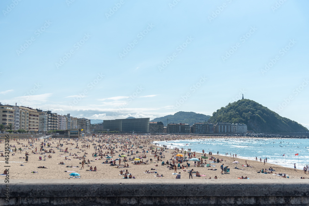 Playa de la Zurriola de San Sebastian en un día soleado de verano llena de gente.  