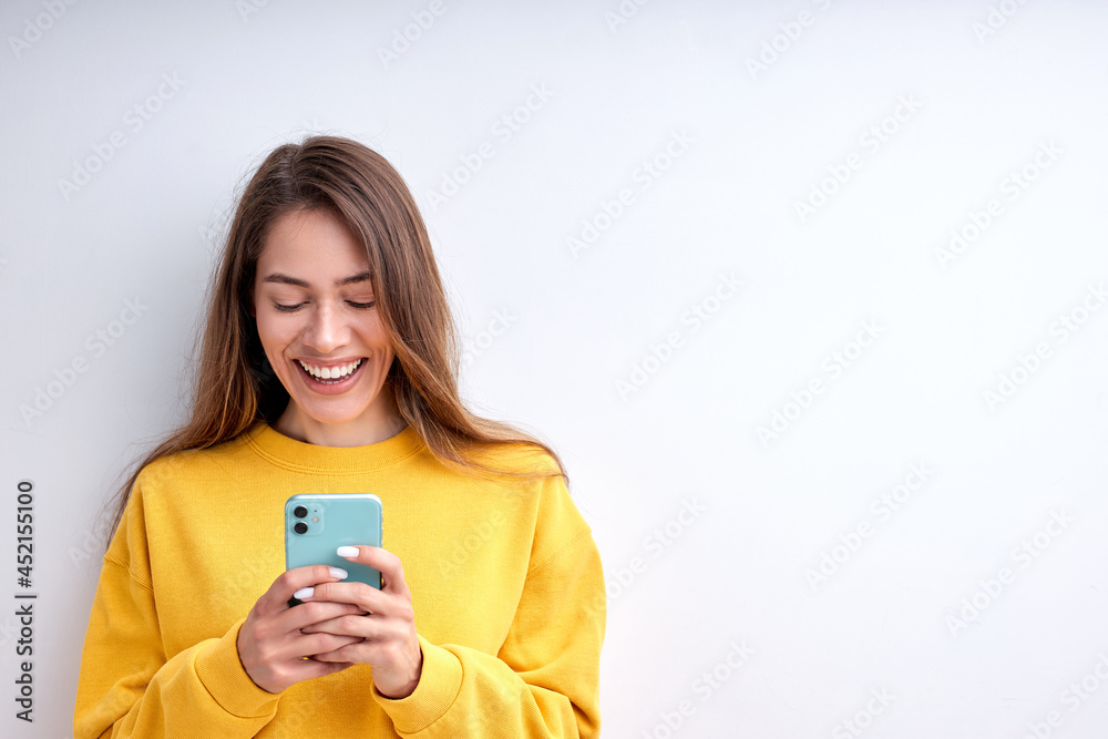 Beautiful pretty caucasian woman in casual wear chatting with friend on smartphone isolated on white studio background. Cute Female with long hair smiling, typing message, feel happiness. Copy space Beautiful pretty caucasian woman in casual wear chatting with friend on smartphone isolated on white studio background. Cute Female with long hair smiling, typing message, feel happiness. Copy space
