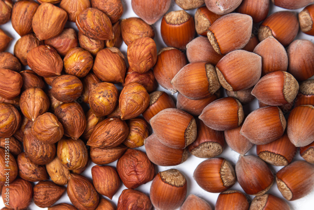 Peeled hazelnuts next to a whole hazelnut on a white background. Healthy diet Peeled hazelnuts next to a whole hazelnut on a white background. Healthy diet