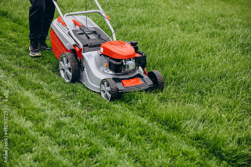 Man cutting grass with lawn mover in the back yard