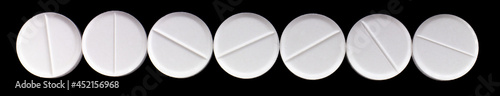 white, round pills on a black background. macro photo