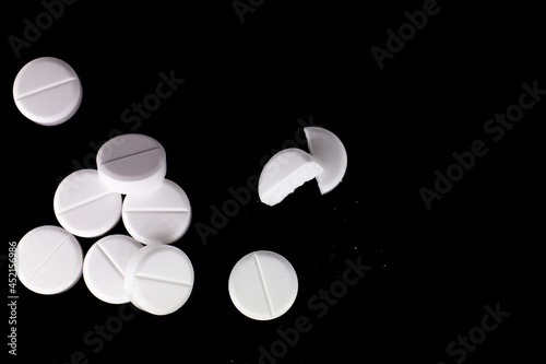 white, round pills on a black background. macro photo