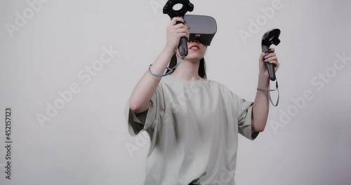 Asian girl in virtual reality glasses with joysticks plays in a 5D attraction photo