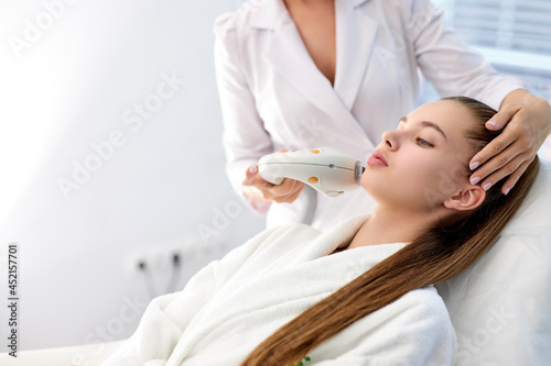 Fotografia female lying in spa salon getting massage for face with professional apparat, lovely caucasian woman in beauty and spa concept