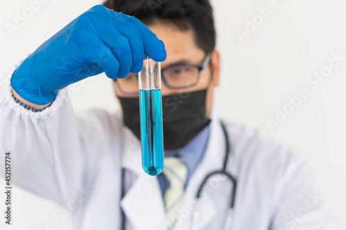 Blue gloved scientist hands holding a bottle with laboratory glassware in a doctor's science lab research and development concept.
