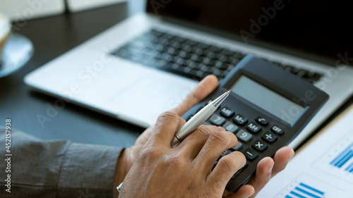 a businessman's hand holds a pen and presses a calculator to calculate financial accounts