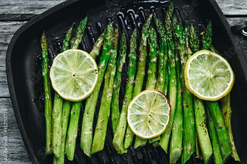 Grilled asparagus. Baked or grilled green asparagus with lemon in black cast iron pan