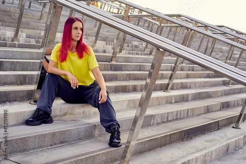 girl in sports clothes is sitting on the steps after a workout in the city