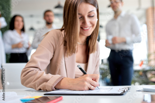 Foto Positive business lady signing financial contract, put write signature on legal corporate paper fill document form buy insurance loan, making business agreement, close up view