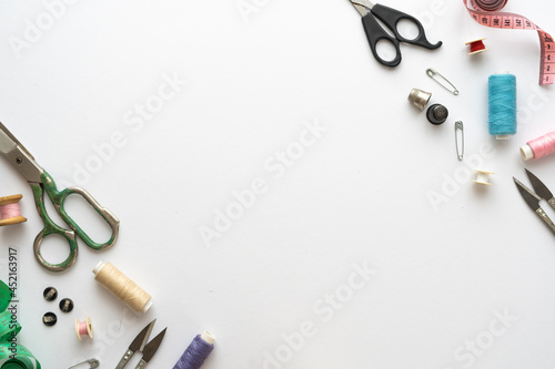 Flat lay composition with scissors and other sewing accessories on white background. Space for text