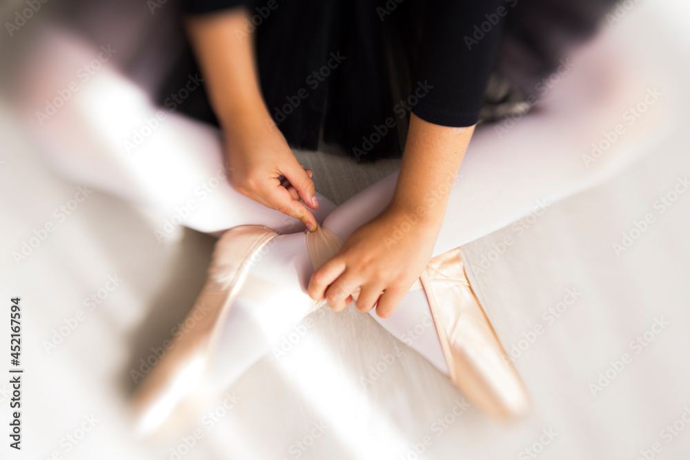 Obraz premium Legs and black fluffy skirt of little balerina wearing pail pink pointe shoes with ribbons