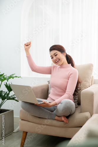 Free Download Beautiful of portrait asian young woman excited and glad of success with laptop on sofa - GFXLoad