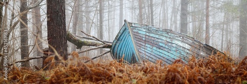 Abandoned old blue wooden boat in a mysterious winter forest. Mossy trees in a white mist. Fresh snow and golden autumn leaves. Concept art, economic decline, recession, philosophy, contrasts, paradox
