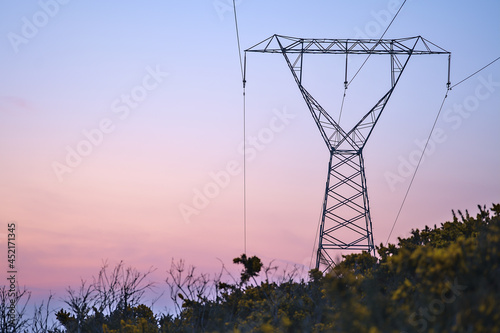 Beautiful early morning view of power lines with electricity transmission pylon against epic purple sunrise sky in Ticknock Forest National Park, County Dublin, Ireland. Soft and selective focus