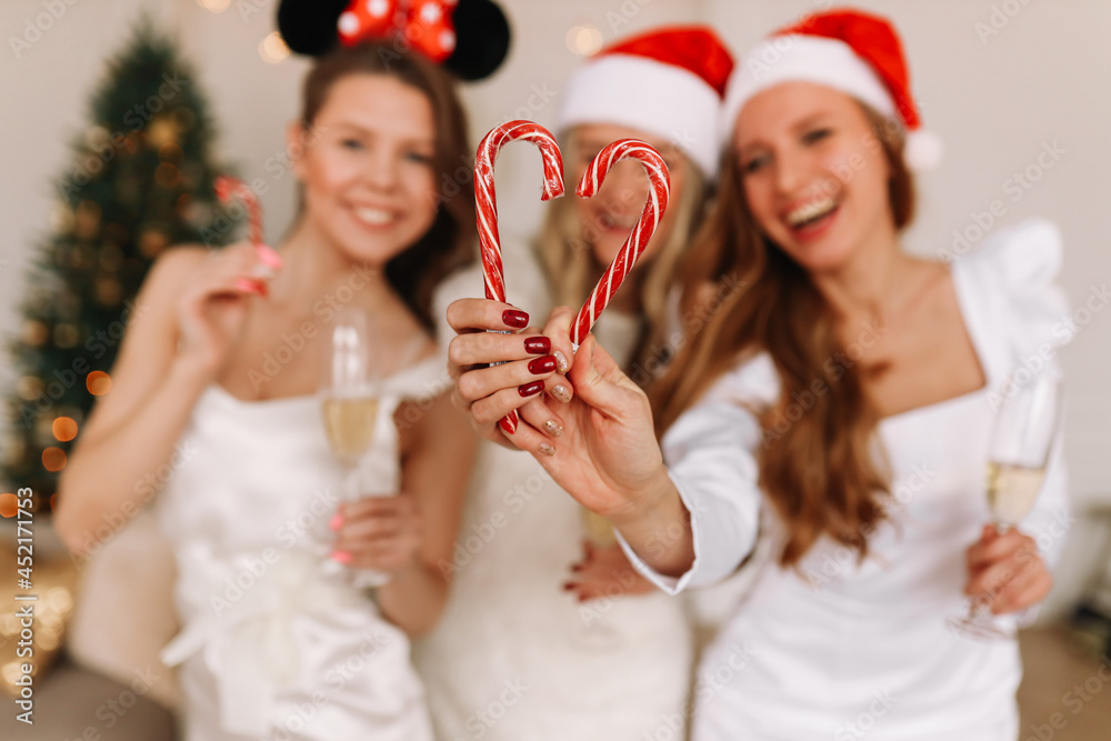 A group of happy cheerful women in elegant outfits having fun laughing drinking champagne celebrating Christmas at a holiday party at home, selective focus A group of happy cheerful women in elegant outfits having fun laughing drinking champagne celebrating Christmas at a holiday party at home, selective focus